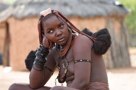 KAMANJAB, NAMIBIA - FEB 1, 2016: Young unidentified Himba woman with the typical necklace and hairstyle shown in himba tribe villageのeditorial素材