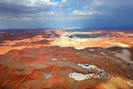 Aerial view of high red dunes and rain on background, located in the Namib Desert, in the Namib-Naukluft National Park of Namibia, Africaの写真素材