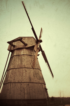 Traditional european old wooden windmill. Retro style photo effect applied. Toned, filtered, grunge and blured cornersの写真素材