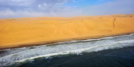Aerial view on the coast in Namibia where dunes of the Namib desert meet with Atlantic ocean, Africaの写真素材