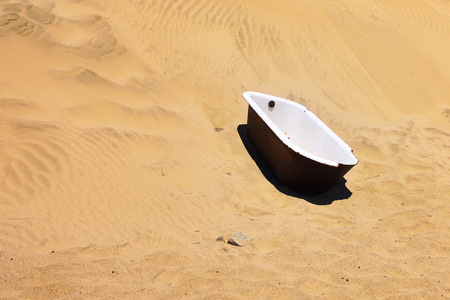 The abandoned bathtub in the sand desert in the ghost diamond town of Kolmanskop in Namibia, which is slowly being swallowed by the desertの写真素材