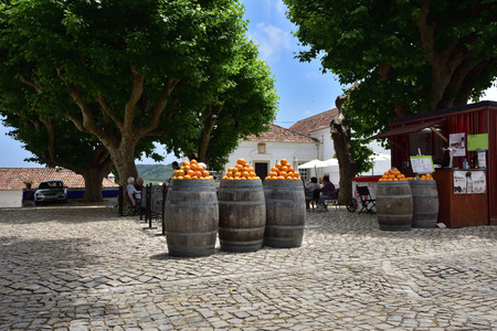 Obidos, Portugal - June 1, 2017: Heap of bright ripe oranges at the barrels on the small square of the medieval city of Obidos, Portugalのeditorial素材