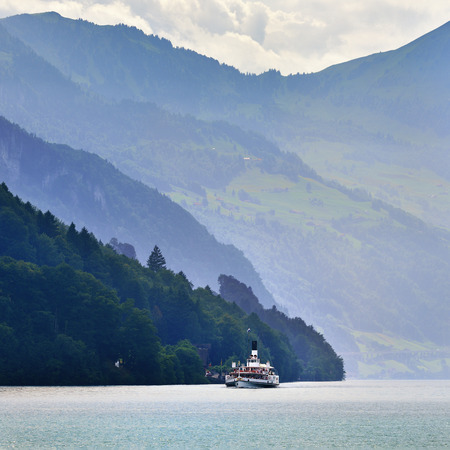 Lucerne, Switzerland - June 14, 2017: Vintage Swiss paddle wheel steamer carrying many passengers on lake Lucerne. By fog covered Alps mountains peaks on background. Switzerlandのeditorial素材
