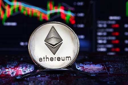 Ethereum. Crypto currency. Ethereum real coin on the computer board and a chart on background....