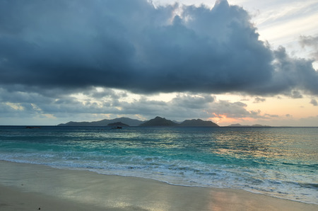 Sunset over indian ocean, Seychelles island, La Digue. Beach Anse Severe. Praslin island on backgroundの写真素材