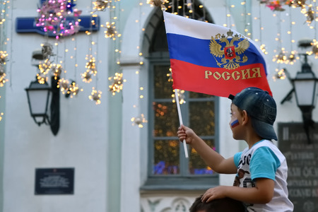 Moscow, Russia - June 23, 2018: Russian young football fan boy with waving national russian flag on the Nikolskaya street in Moscow. FIFA world cup, Mundial 2018のeditorial素材