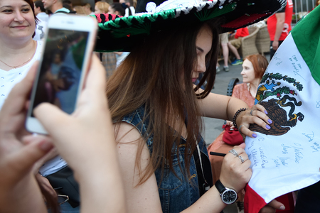 Moscow, Russia - June 23, 2018: Russian football fan girl writing autograph on Mexican national country flag. The Nikolskaya streets in Moscow, FIFA world cup, Mundial 2018のeditorial素材