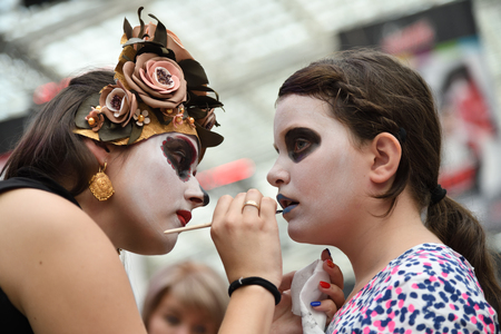 Moscow, Russia - June 29, 2018: The girl participant makes the sugar skull makeup on face other girl during Dia de los Muertos Mexican carnival. Day of The Deadのeditorial素材