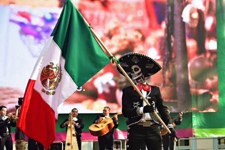 Moscow, Russia - June 29, 2018: Man in hat with sugar skull makeup waving mexican flag during Dia de los Muertos Mexican parade. Day of The Deadのeditorial素材