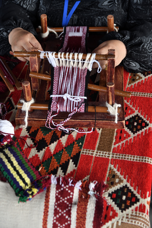 A senior arabian woman makes a traditional sadu weaving. Hands of a weaver close-up, focus on the frame. Qatarの写真素材