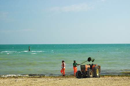 Abruzzo, Italy - July 04, 2006: Workers remove seaweed and other trash from the beachのeditorial素材
