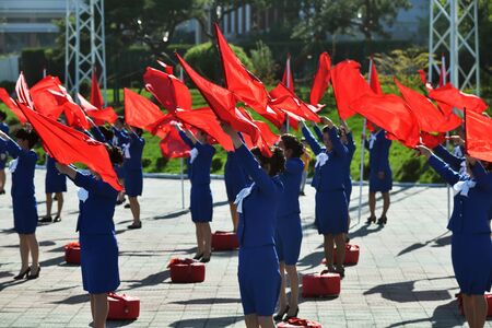 Pyongyang, North Korea - May 2, 2019: Girls with red flags  perform morning show on the streets of the city to create a good mood among citizensのeditorial素材