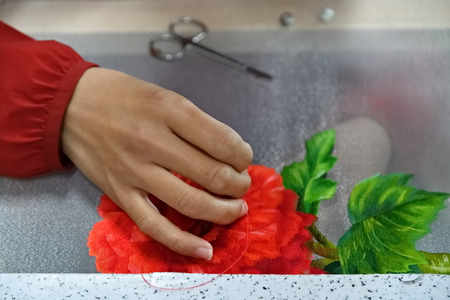 Embroidered hand with needle and silk thread over canvas with exotic flowers close upの写真素材