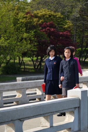 Pyongyang, North Korea - May 1, 2019: Young girls, members of the Kimilsungist-Kimjongilist Youth League walking on a city streetのeditorial素材