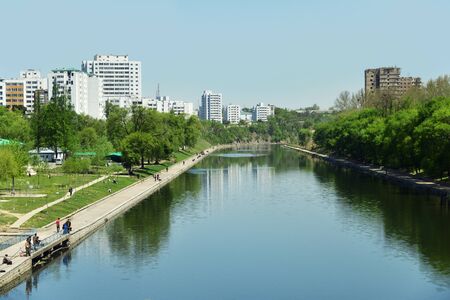 Pyongyang, North Korea - May 2, 2019: Pyongyang suburb. Local people fishing in Taedong River creek. Park and residential districts and construction site in backgroundのeditorial素材