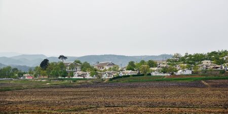 North Korea - May 4, 2019: Typical houses of peasants built by the state for residents of countryside. North Korea. DPRK. Village and plowed fields around shown at dawnのeditorial素材
