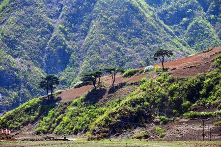 Wonsan region, North Korea - May 3, 2019: Mountains, power line, propaganda banners and plowed agriculture fields on the mountain slope. Typical countryside viewのeditorial素材