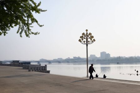 Pyongyang, North Korea - May 1, 2019: Locals fishermen catch a fish on waterfront on Kim Il Sung square at the morningのeditorial素材