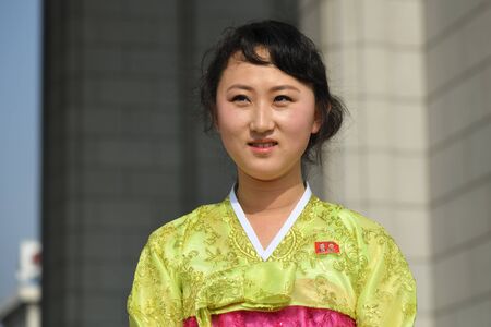Pyongyang, North Korea - May 1, 2019: Local girl in traditional korean dress, member of the Korean Workers Party shown on a city streetのeditorial素材