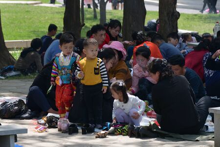 Pyongyang, North Korea - May 1, 2019: Happy families having fun outdoor at bbq picnic with snacks, food and drink. Local people enjoying spring time together at barbecue park partyのeditorial素材