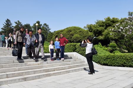 Pyongyang, North Korea - May 1, 2019: People on the stairs in the urban park area. Mom takes pictures of their children. Family helps grandma come downのeditorial素材