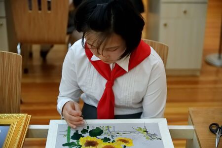 Pyongyang, North Korea - May 2, 2019: Korean pioneer girl embroiderers a picture in the Pyongyang Palace of schoolchildren. Extracurricular educational institution in Pyongyangのeditorial素材