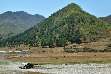 North Korea - May 3, 2019: Countryside landscape, Village, cultivated agricultural field and mountain at background. Truck and people in the foregroundのeditorial素材
