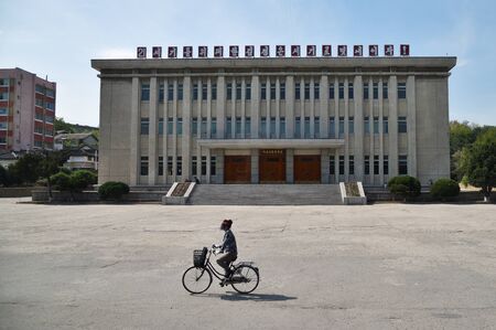 Gaeseong, North Korea - May 5, 2019: Urban life. Woman rides bicycle on their own business on a city...