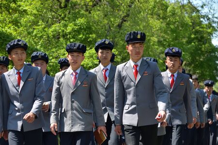 North Korea, Pyongyang - May 1, 2019: A group of North Korean workers in identical suits marching along the road. DPRKのeditorial素材