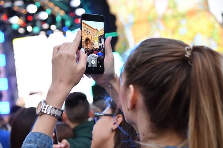Moscow, Russia - Sept 7, 2019: Girl filming on smartphone a festive show on Tverskaya street in honor 872 anniversary of the founding of Moscow. Focus on phoneのeditorial素材