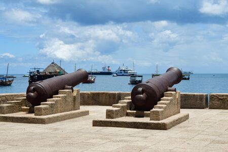 Waterfront of Stone Town with old cannons in Zanzibar and boats in ocean on the background. Tanzania, Africaの写真素材