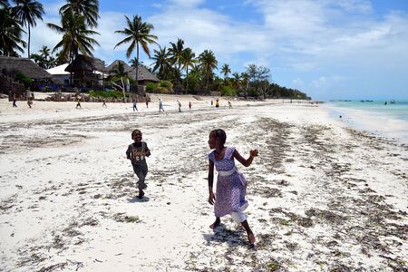 Pingwe, Zanzibar - October 6, 2019: Cheerful happy children play on the Pingwe beach, local village on background. Tanzania, Africaのeditorial素材
