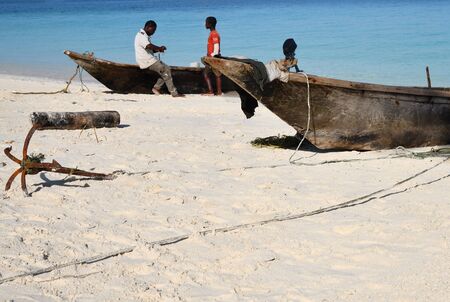 Kendwa, Zanzibar - October 6, 2019: Two of local fishermen near wooden boat. Tanzania, Africa. Focus on the foregroundのeditorial素材