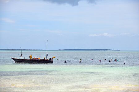 Kendwa, Zanzibar - October 4, 2019: Local women in traditional dress fishing in the ocean during low tide. Tanzania, Africa. Selective focusのeditorial素材
