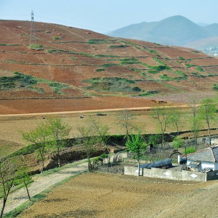 Countryside landscape, North Korea. Village, cultivated agricultural field and mountain at backgroundの写真素材