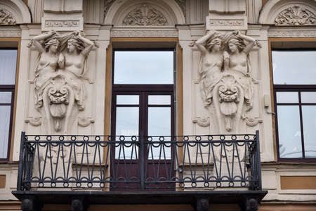 Beautiful facade of an old building with balcony and naked nymph sculptures. St. Petersburg, Russiaのeditorial素材