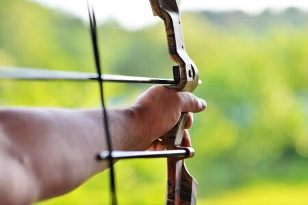 Man's hand over blur background of Archery with a bow in the foreground during an archery...
