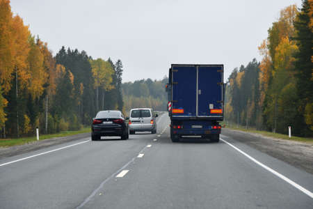 Karelia, Russia - September 30, 2020: Truck and other cars go along the highway through the autumn...