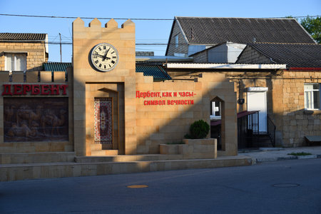 Derbent, Russia - 24 July, 2022: Clock on the house wall in old city. Cyrillic inscription on the wall means - Derbent, like a clock, is a symbol of eternity. Republic of Dagestanのeditorial素材