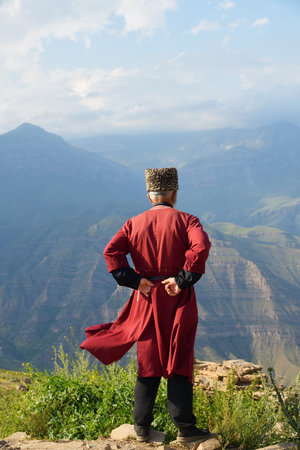 Local man in national tradition dress standing in profile against Caucasian mountains in village of Goorのeditorial素材