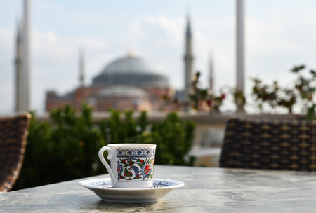 A cup of coffee on the table against the backdrop of the Hagia Sophia mosque in Istanbul on winter day. View from city roofs cafeの写真素材