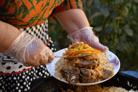 Traditional Uzbek oriental cuisine, pilaf or plov with large pieces of meat and carrots, cooked in a...