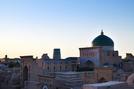 View to Mausoleum of Pahlavon Mahmoud.. Cityscape in Ichan Kala at sunset time, ancient inner town of the old city Khiva in Khorezm region, Uzbekistanの写真素材