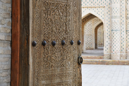Beautiful ancient carved wooden door with massive metal handle. Besh Khovli palace. Khiva, Uzbekistanの写真素材