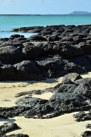 The rocky shore of Mauritius island. View on the Coin de Mire island