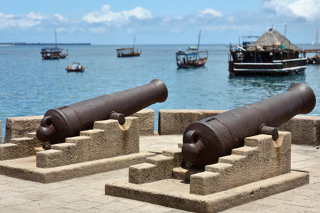 Waterfront of Stone Town with old cannons in Zanzibar and boats in ocean on the background. Tanzania, Africaの写真素材