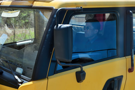 Wonsan region, North Korea - May 3, 2019: Driver in the yellow heavy truck cabin on a countryside...