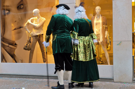 Venice, Italy - March 06, 2011: A couple of passersby in 18th-century costumes look into the window of a modern fashion store. Venezia in Italy, famous UNESCO World Heritage Siteのeditorial素材