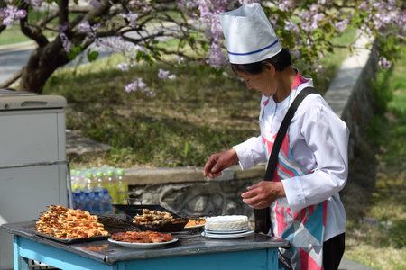 Pyongyang, North Korea - May 1, 2019: Female seller of roast meat shown in the Taesongsan Funfair. Is an amusement park located in Taesong-guyokのeditorial素材