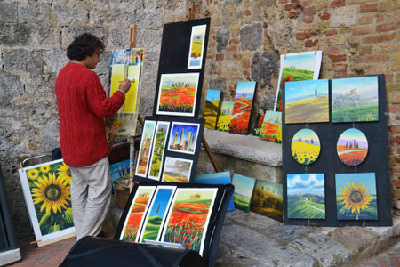 San Gimignano, Italy - October 10, 2012: Street artist paints a arts for sale in the small medieval town with many medieval Skyscrapers - towers, it is a famous Unesco World Heritage site in Tuscanyのeditorial素材